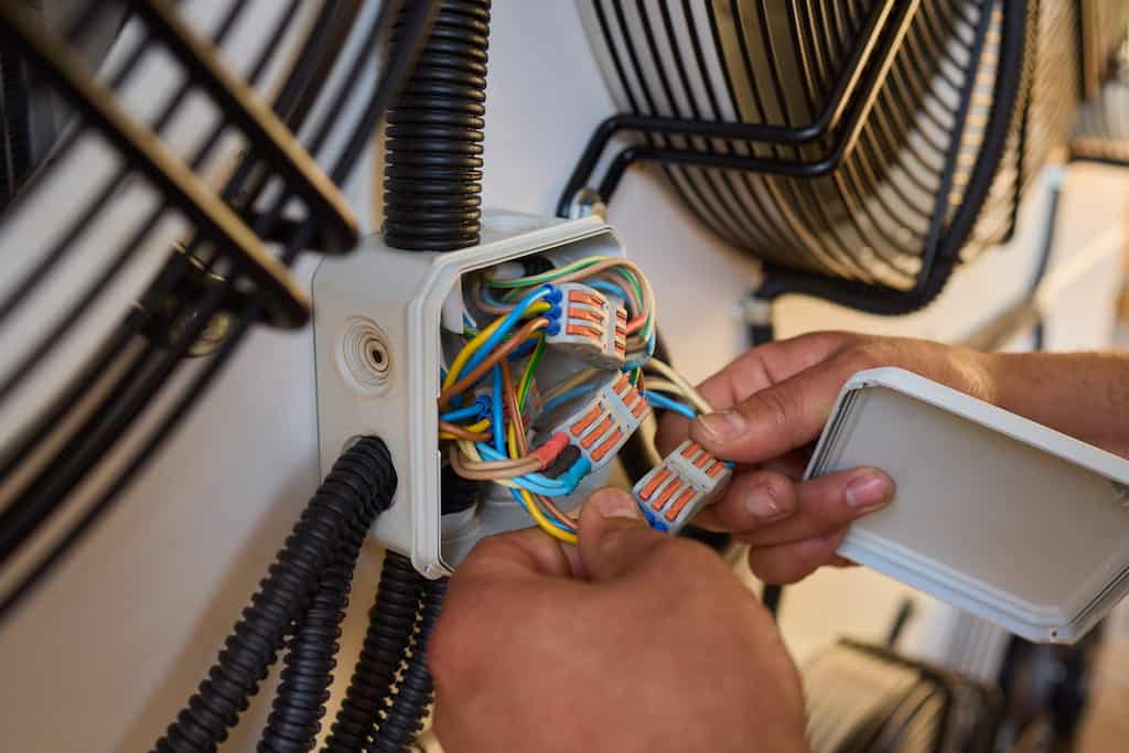 An electrician connecting wires inside an electrical junction box